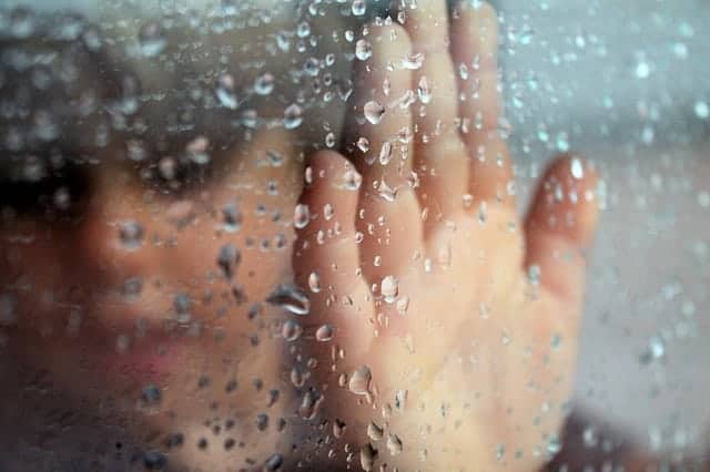 hand on rain covered window